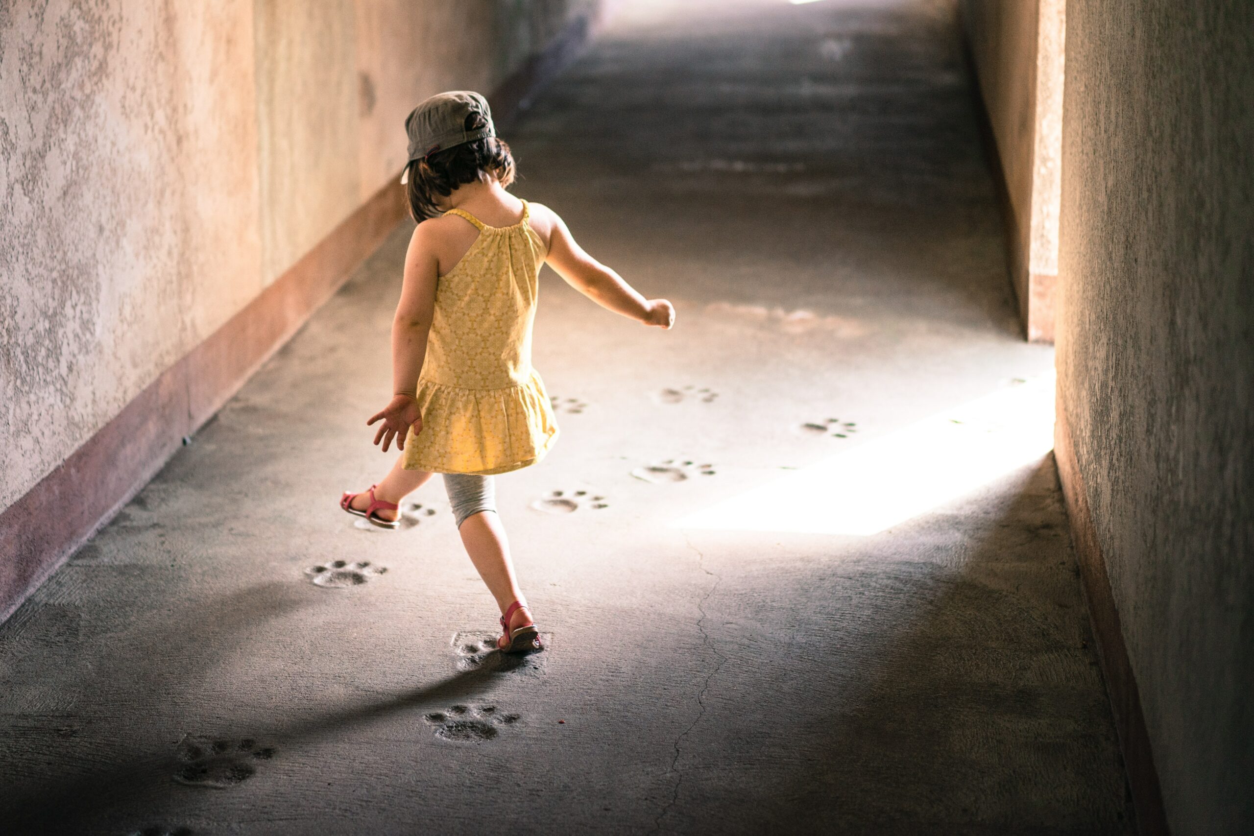 5 askelta toimivaan myyntikirjeeseen -artikkelin kuva, jossa pieni tyttö keltaisessa mekossaan astelee betoniin jääneitä eläimenjälkiä pitkin.